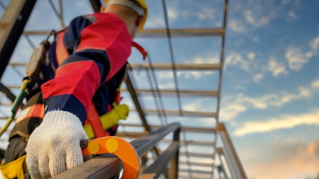 Small business owner following OSHA regulations to scale a ladder. 