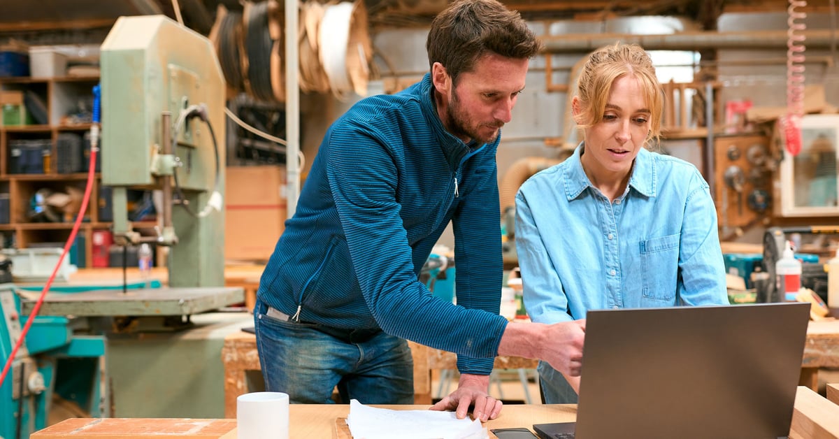 Two small business owners consult a computer. 